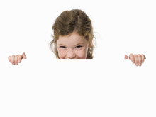 Young Girl Peeking Over White Sign