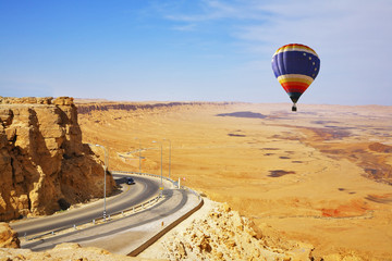 Poster - The bright decorative balloon soars above road to desert