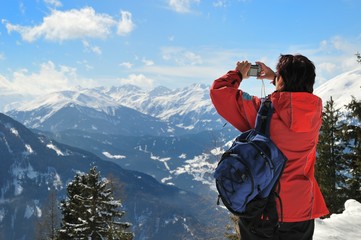 Senior woman taking picture in snow landscape