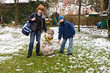 © travelview - Kinder stehen neben ihrem tauenden Schneemann