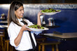 © Kablonk Micro - Hispanic waitress in restaurant serving salad plates