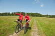 © CandyBox Images - Sportive couple riding mountain bike in meadow