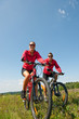 © CandyBox Images - Sportive couple riding mountain bike in meadow