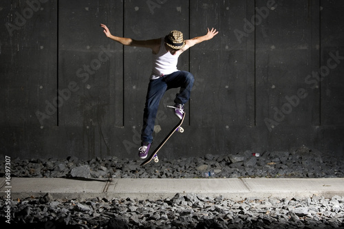 Fotografie, Obraz Skateboarder doing an ollie on walking path