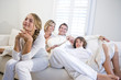 © Kablonk Micro - Family sitting together on white sofa watching television