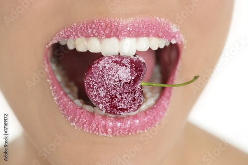 Fototapeta na wymiar Cherry with sugar between woman teeth
