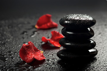 spa stones and rose petals over black background