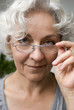 attraktive Seniorin schaut hinter Brille hervor