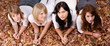 © aldegonde le compte - groupe de quatre filles couché dans des feuilles d'automne