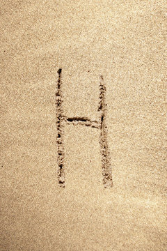 Alphabet letter H handwritten in sand