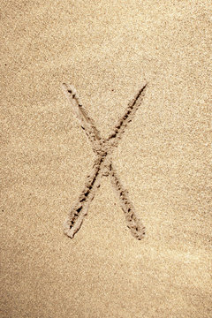 Alphabet letter X handwritten in sand