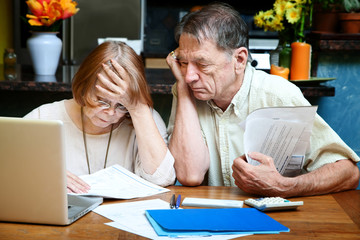 Senior couple at home with many bills