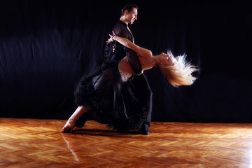 dancers in ballroom against black background