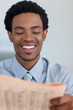 © WavebreakMediaMicro - Smiling Afro-American businessman reading a newspaper