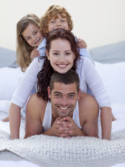 Wall Mural - Portrait of happy parents and children having fun in bed