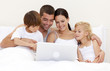 © WavebreakMediaMicro - Family using a laptop in bed