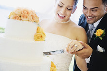Multi-ethnic Bride And Groom Cutting Cake