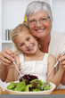 © WavebreakMediaMicro - Happy grandmother eating a salad with granddaughter