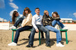 © hurricanehank - Group of five smiling young people sitting on a bench