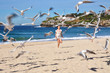 Beautiful young girl runs on Bondi Beach, chasing seagulls