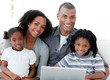 © WavebreakMediaMicro - Happy Afro-American family using a laptop in the living-room