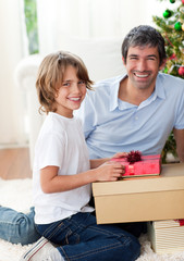 Smiling father and his son opening Christmas presents