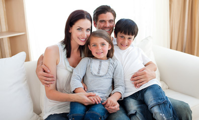 Wall Mural - Portrait of a smiling family sitting on the sofa