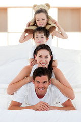 Wall Mural - Parents and children playing on bed together