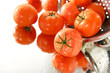 dojrzale czerwone pomidory w sitku, na białym tle, mokre, lustro