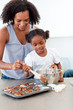 © WavebreakMediaMicro - Afro-american little girl preparing biscuits with her mother