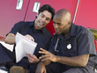 © Monkey Business - Two paramedics cheerfully doing paperwork, sitting by ambulance