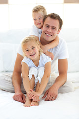 Cute blond boy hugging his dad sitting on a bed