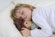canvas print picture - Kleines Maedchen liegt mit Puppe schlafend im Bett.