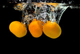 Fototapeta Łazienka - Fresh tangerines dropped into water with bubbles on black