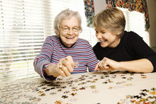 Elderly Woman And Younger Woman Doing Puzzle