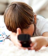 Wall Mural - Cute little boy watching TV lying on the floor