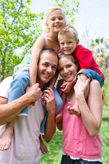 Wall Mural - Happy parents giving their children piggy-back ride