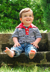 Cute smiling child sitting in a summer garden