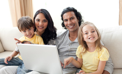 Wall Mural - Jolly family using laptop on sofa