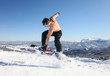 Snowboarder jumps up at mountain top