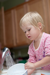 3 years old girl washing the dishes