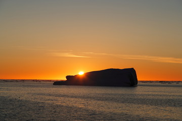 Wall Mural - Sunset in Greenland behind iceberg. Arctic ocean.