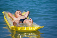 Boy In Swimming Trunks Relaxing On An Inflatable Mattress