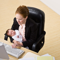 Wall Mural - Businesswoman holding baby at desk