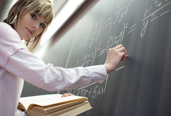 pretty college student/young teacher in front of a chalkboard