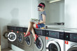 Junge Frau sitzt auf einer Waschmaschine