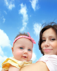 Wall Mural - Happy mother with a baby over blue sky