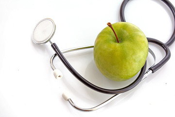 Stethoscope and green apple on white background