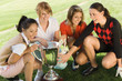 four female golfers crouching around trophy (elevated view)
