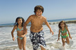 children in swimwear running through waves